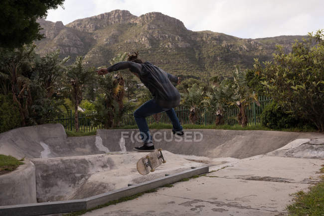 Vista trasera del skateboarding de hombre en el parque de skate - foto de stock