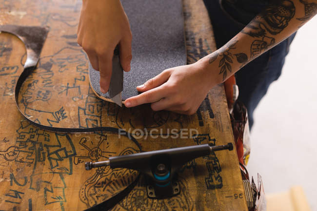 Крупный план женщины, ремонтирующей скейтборд в мастерской — стоковое фото