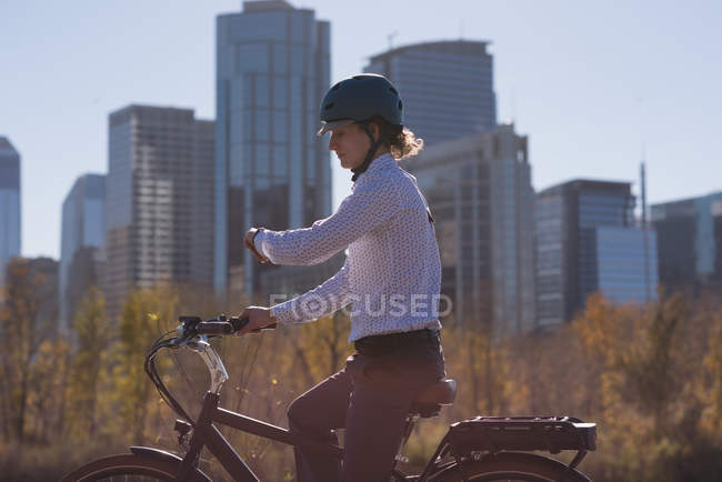 Man checking time while riding bicycle on the road in the city — Stock Photo