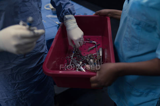 Sección media del cirujano que sostiene herramientas médicas en el hospital - foto de stock