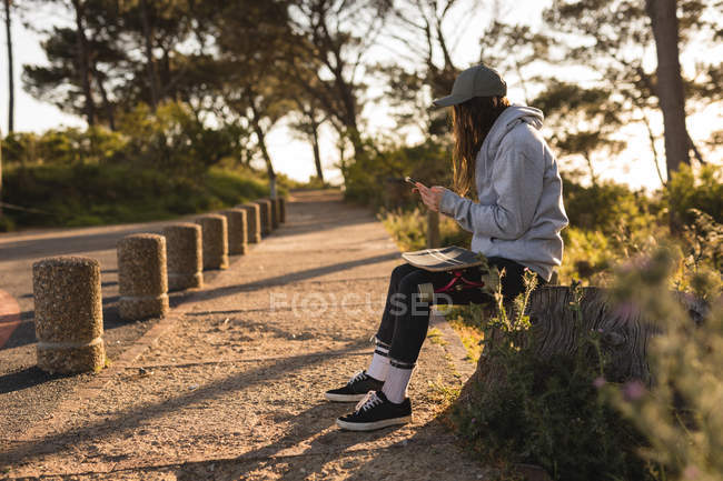 Молода жінка скейтбордистка використовує мобільний — стокове фото