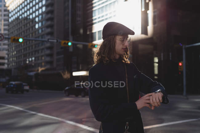 Человек проверяет время на вахте во время прогулки по улице в городе — стоковое фото