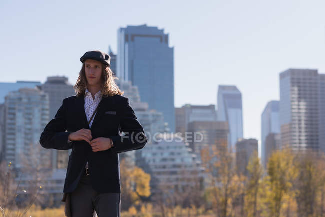 Чоловік натискає свій костюм, стоячи на дорозі в місті — стокове фото