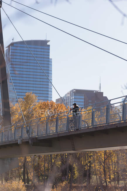 Продуманий чоловік стоїть з велосипедом на мосту в місті — стокове фото