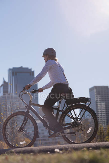 Vista lateral do homem andando de bicicleta na estrada na cidade — Fotografia de Stock