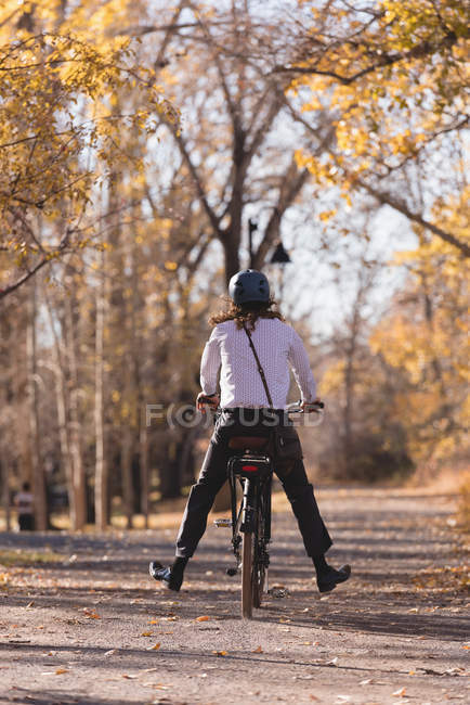 Rear view of man riding bicycle on a road in the park — Stock Photo