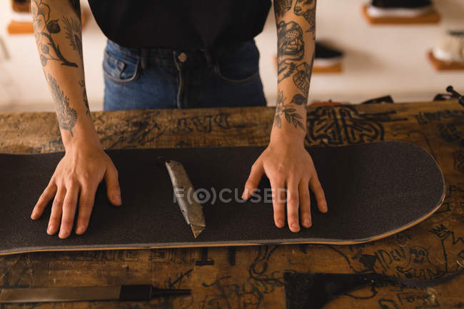 Partie médiane de la femme réparer skateboard dans l'atelier — Photo de stock