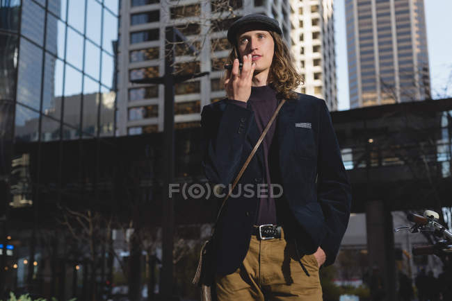 Человек разговаривает по мобильному телефону во время прогулки по улице в городе — стоковое фото