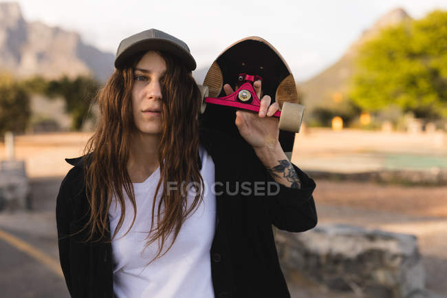 Retrato de skatista feminina carregando skate nos ombros — Fotografia de Stock