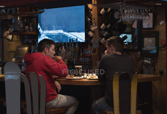 Jóvenes amigos comiendo comida en el pub - foto de stock