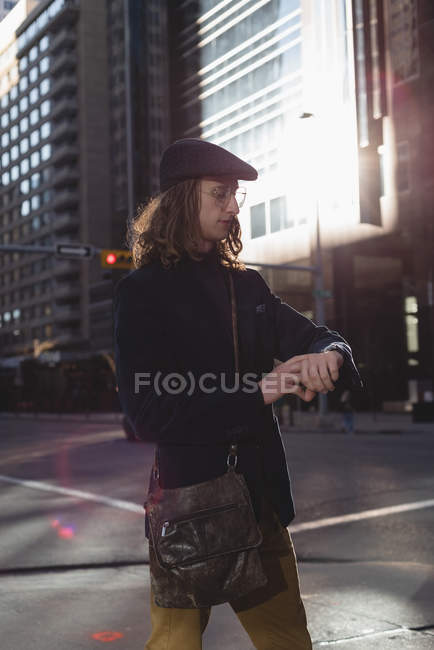 Man checking time on watch while walking on the street in the city — Stock Photo