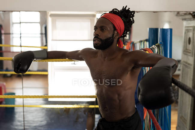 Tired male boxer relaxing in boxing ring at fitness studio — Stock Photo
