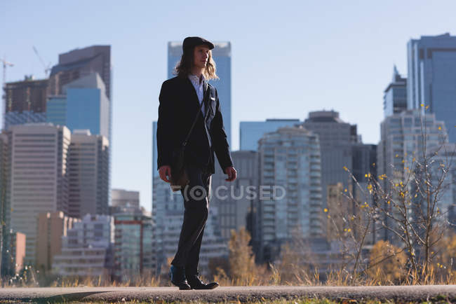 Молодий чоловік, що йде по дорозі в місто — стокове фото