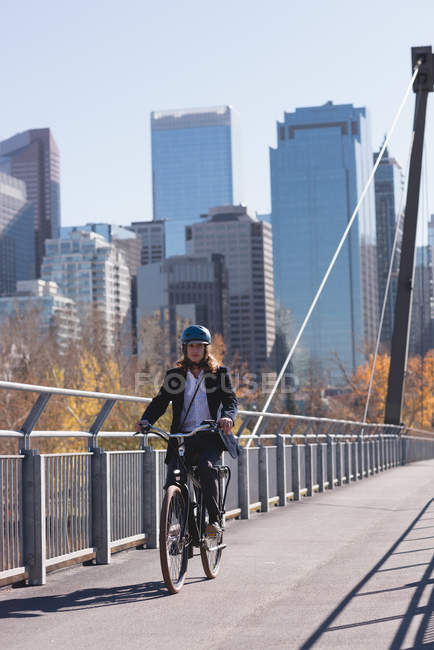 Молодий чоловік їде на велосипеді на мосту в місті — стокове фото