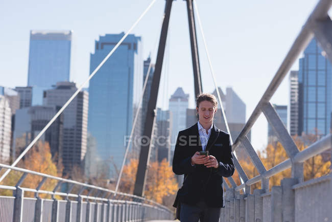 Man using mobile phone while walking on the bridge in the city — Stock Photo