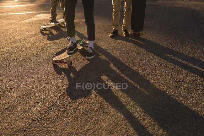 Low section of skateboarders skating on country road — Stock Photo