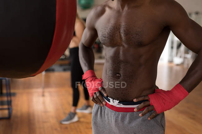 Partie médiane du boxeur masculin debout avec les mains sur les hanches dans le studio de fitness — Photo de stock