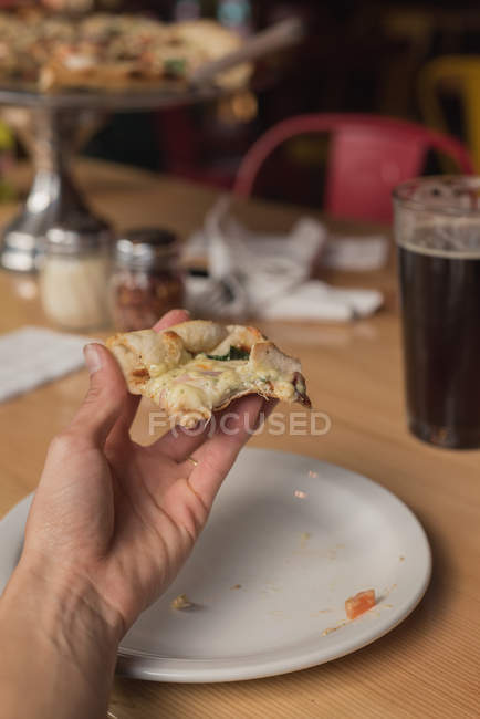 Close-up of man holding slice of pizza in hand — Stock Photo