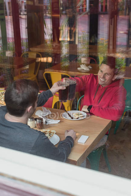 Счастливые друзья поднимают тосты за пивные бокалы в пабе — стоковое фото