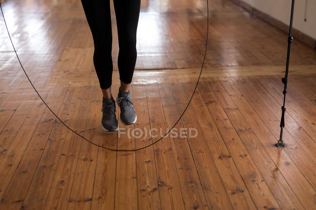 Baixa seção de boxeador feminino exercitando com pular corda no estúdio de fitness — Fotografia de Stock