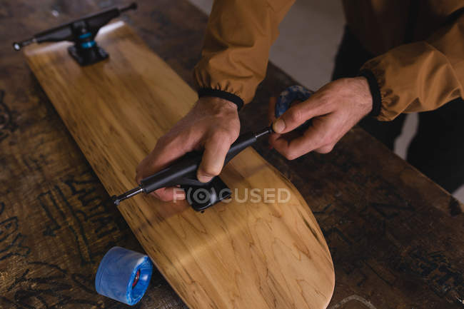Close-up of man repairing skateboard in workshop — Stock Photo