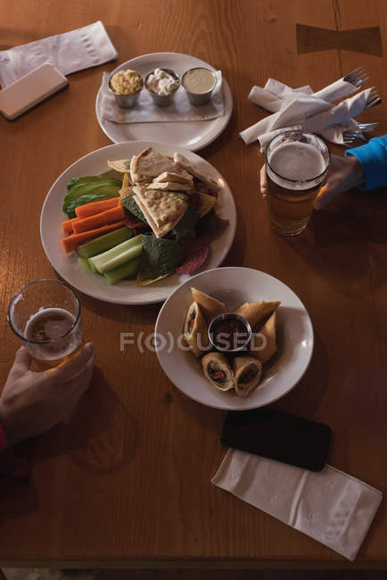 Vue en angle élevé d'amis tenant des verres à bière sur la table dans un pub — Photo de stock