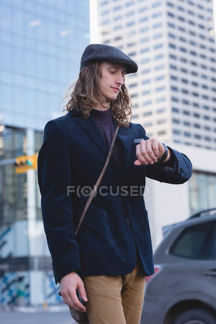 Чоловік перевіряє час на годиннику під час прогулянки по вулиці міста — стокове фото