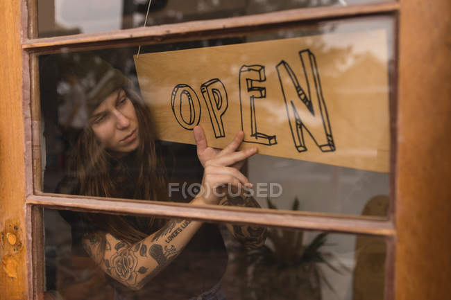 Young woman flipping open signboard in workshop — Stock Photo