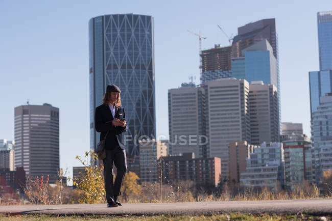 Man using mobile phone while walking on a road in the city — Stock Photo