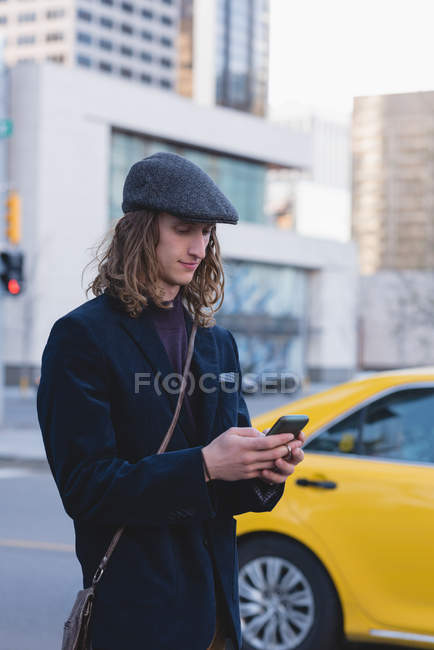 Hombre usando el teléfono móvil mientras camina por la calle en la ciudad - foto de stock