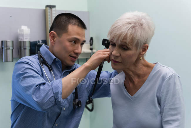 Front view of young Asian male doctor examining a senior patient in the clinic — Stock Photo