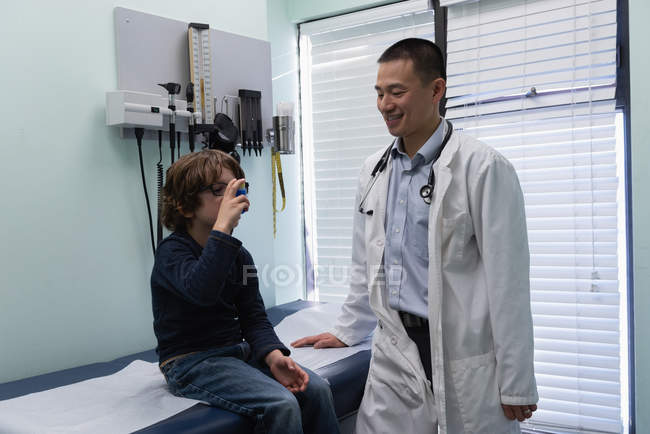Paziente ragazzo caucasico in uso inalatore asma in clinica — Foto stock