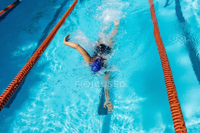 Young female swimmer swimming freestyle in swimming pool — Stock Photo