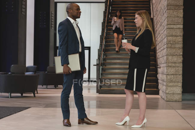 Side view of business people interacting with each other in the lobby at office — Stock Photo
