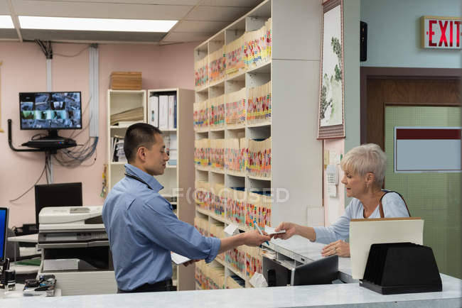 Young Asian male doctor prescribing medicines for patient in clinic — Stock Photo