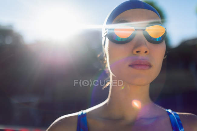Vista frontale di una nuotatrice con occhiali da bagno che guarda lontano in piscina in una giornata di sole — Foto stock