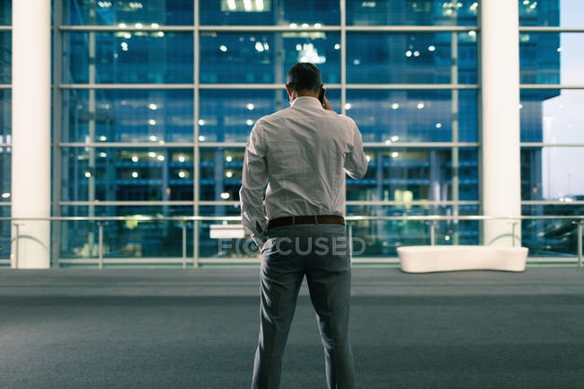 Задній вид бізнесмен, говорити по телефону за межами офісної будівлі за ніч — стокове фото