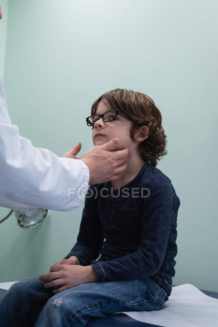Vista laterale del giovane medico maschio asiatico che parla con il ragazzo in clinica — Foto stock
