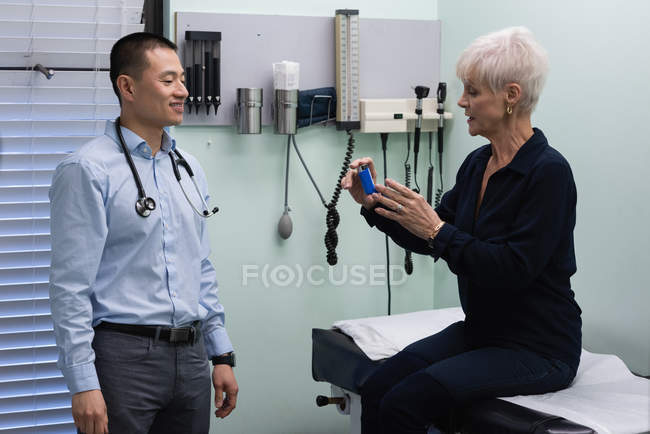Frontansicht junger asiatischer Arzt und Seniorpatient diskutieren über Asthma-Inhalator in Klinik — Stockfoto