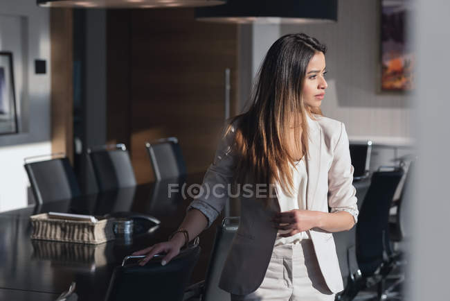 Вид сбоку на вдумчивую деловую женщину, стоящую в конференц-зале офиса — стоковое фото