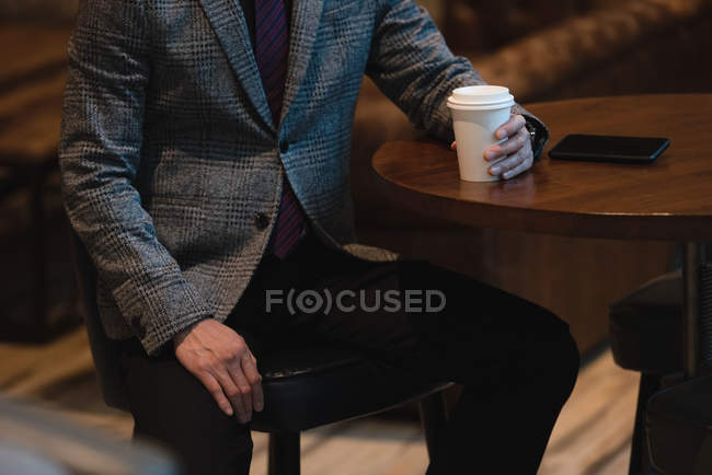 Middle section of businessman having coffee at desk in the office — Stock Photo