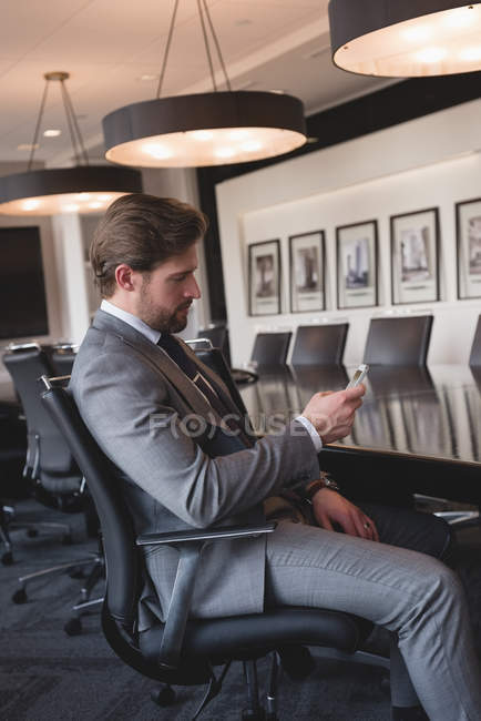 Vista laterale dell'uomo d'affari seduto che utilizza il telefono cellulare nella sala conferenze in ufficio — Foto stock