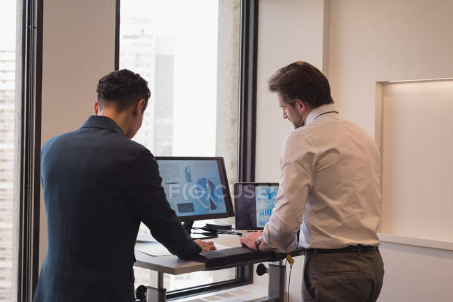 Visão traseira de empresários de pé trabalhando juntos no escritório moderno — Fotografia de Stock