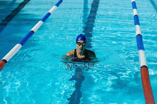 Vista frontal de la joven nadadora parada en la piscina - foto de stock