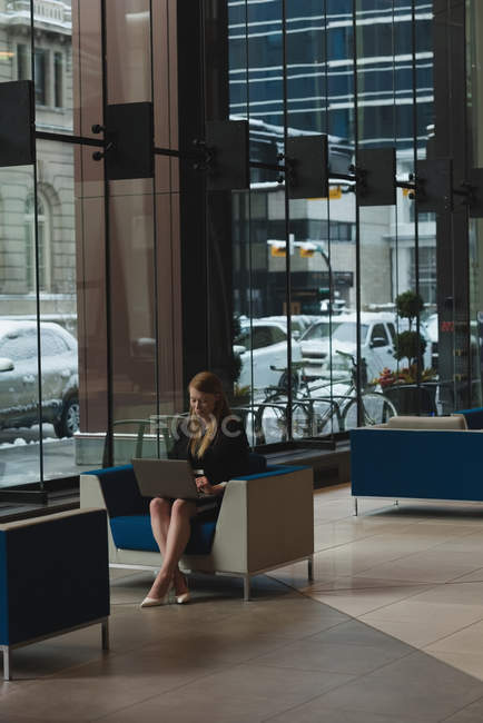 Vista lontana di donna d'affari che usa il computer portatile nella lobby a ufficio — Foto stock