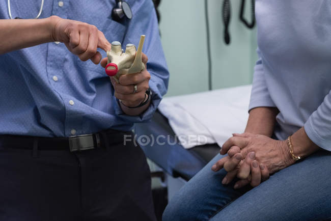 Mid section of young Asian male doctor and senior patient discussing over heart model at clinic — Stock Photo
