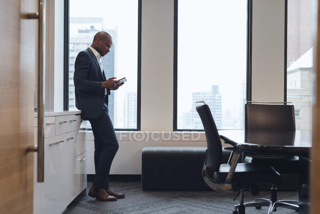 Vista lateral do empresário usando tablet digital na sala de conferências no escritório — Fotografia de Stock
