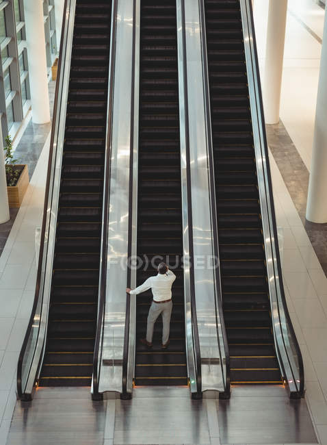 Vue surélevée de l'homme d'affaires sur l'escalier roulant dans le bureau — Photo de stock