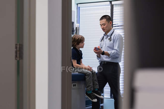 Вид спереду молодого азіатського лікаря, що взаємодіє з хлопчиком у клініці — стокове фото
