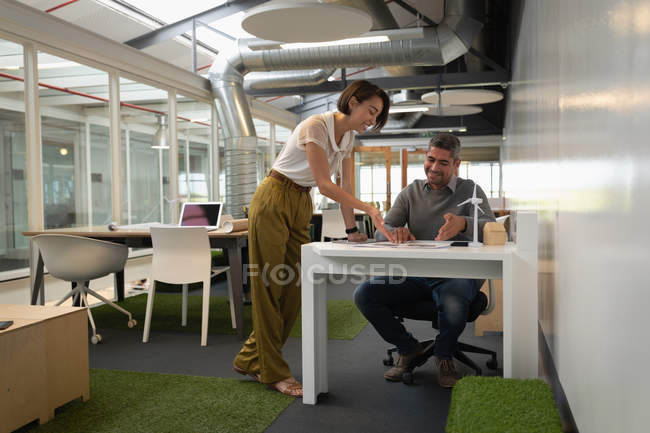 Вид спереду на багато етнічних бізнесменів, які взаємодіють і обговорюють через план в офісі — стокове фото